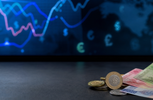 Monedas y billetes mexicanos junto a una pantalla con referencias cambiarias
