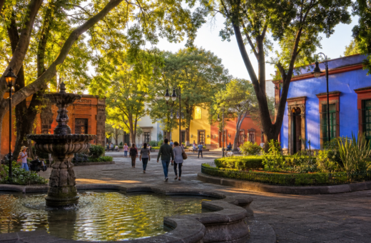 Plaza arbolada de Coyoacán con fuente y arquitectura histórica al amanecer
