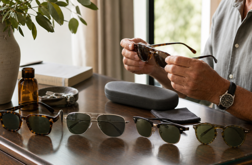 Cuatro estilos de lentes de sol y un estuche sobre una mesa de madera.