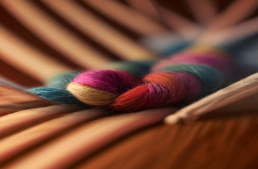 Madejas de estambre de varios colores entrelazadas sobre una superficie de madera, en primer plano